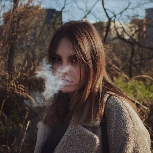 woman looking at camera and blowing out smoke