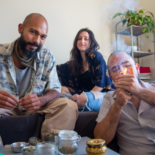 2 men and one women smoking weed and looking at the camera