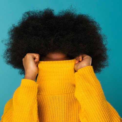 Woman with Afro pulling up her shirt to hide her face