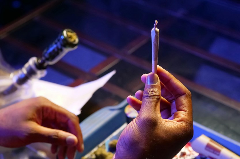 Person holding a joint looking uncertain, cannabis addiction concept