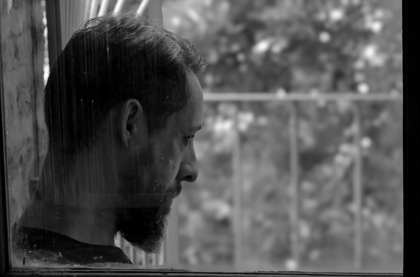 Middle-aged man standing outside a workshop looking calm and thoughtful