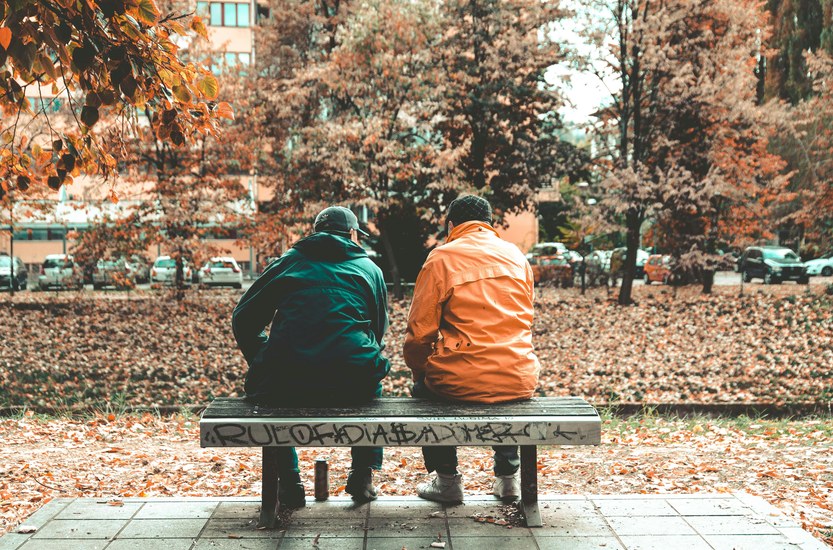 Two men sitting apart on a bench, friendship distance after quitting weed