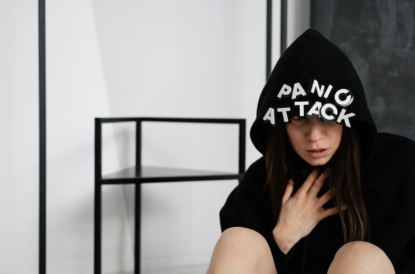 Person sitting against a wall breathing slowly, dealing with a panic attack, indoor setting