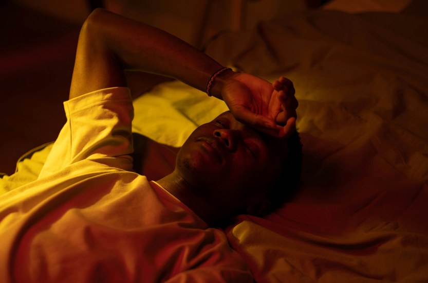 Person lying awake in bed at night looking uncomfortable, sweating during weed withdrawal