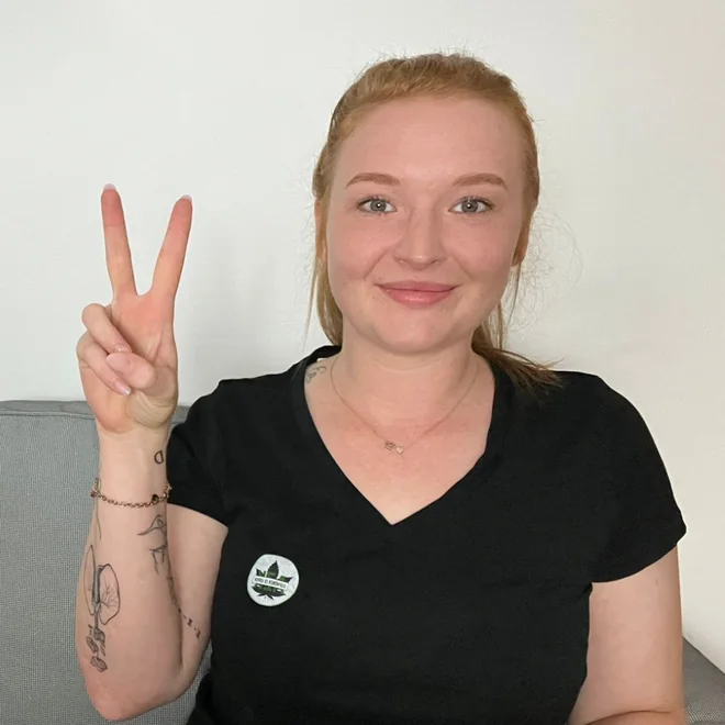 Smiling young woman with red hair making a peace sign