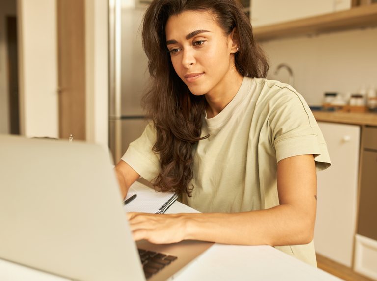 Woman sitting at the kitchen table with a laptop