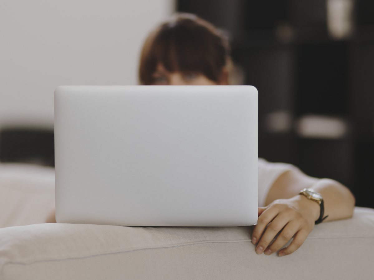Woman sitting behind her laptop on the sofa